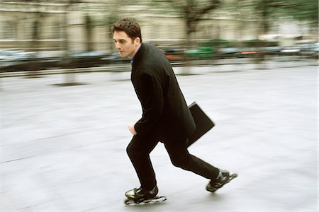 rollerskating - Man in business attire inline skating carrying briefcase in city square Stock Photo - Premium Royalty-Free, Code: 695-05769985