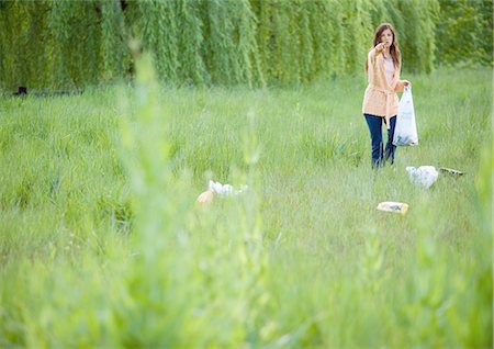 dirty environment - Woman picking up litter in field, pointing at camera Stock Photo - Premium Royalty-Free, Code: 695-05762318