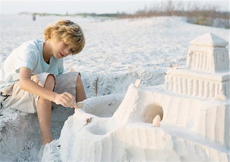 Boy putting finishing touches on sand castle Stock Photo - Premium Royalty-Free, Code: 695-05762380