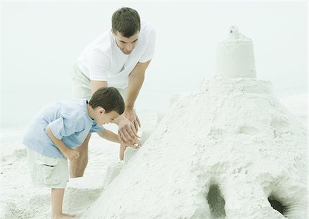 Father and son building sand castle at the beach Stock Photo - Premium Royalty-Free, Code: 695-05762560