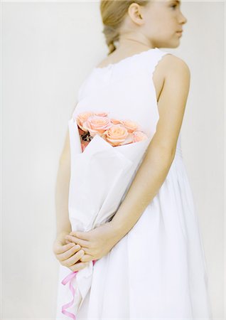 Girl holding bouquet of roses behind back Stock Photo - Premium Royalty-Free, Code: 695-05763211