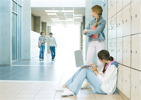 Two high school girls by lockers, watching teen boys approaching Stock Photo - Premium Royalty-Free, Code: 695-05763371