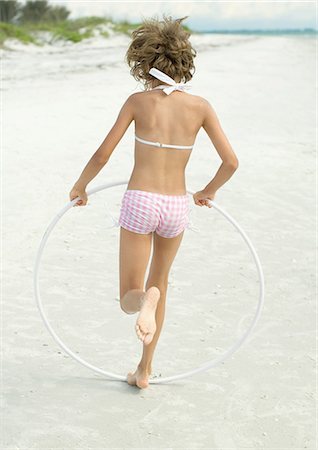 Girl running with plastic hoop on beach Stock Photo - Premium Royalty-Free, Code: 695-05763575