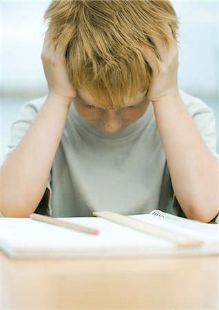 sulky tantrum - Boy holding head and looking down at homework Stock Photo - Premium Royalty-Free, Code: 695-05763643