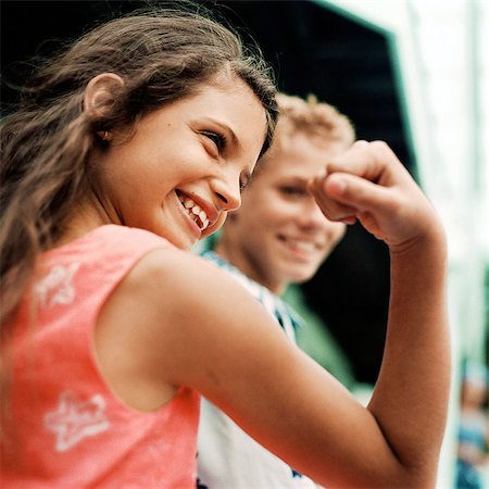 Girl flexing arm muscles, boy in background, smiling Stock Photo - Premium Royalty-Free, Code: 695-05774098