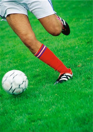 Soccer player's legs, running with ball, low section. Stock Photo - Premium Royalty-Free, Code: 695-05775821