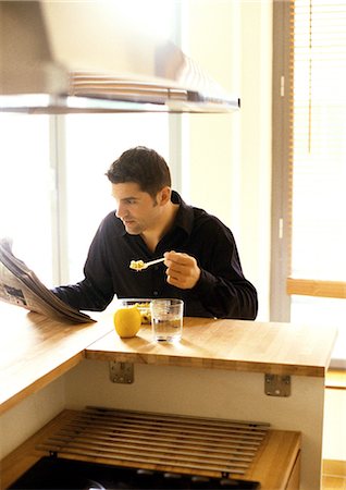 Man eating and reading newspaper Stock Photo - Premium Royalty-Free, Code: 695-05776129