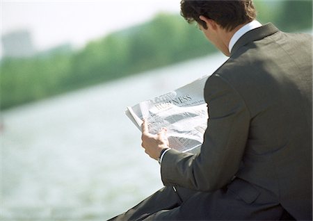 Businessman reading newspaper, outdoors, rear view, tilt Stock Photo - Premium Royalty-Free, Code: 695-05776273