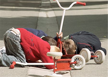 elementary school recess - Three children kneeling, looking at scooter Stock Photo - Premium Royalty-Free, Code: 695-05776454