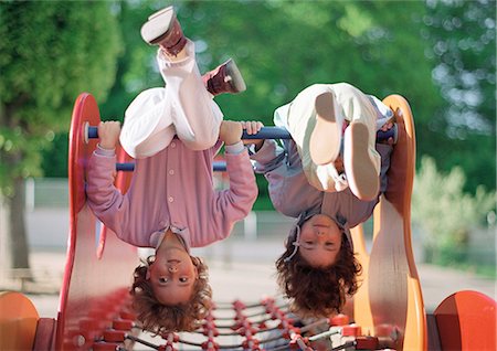 Two children hanging upside down on jungle gym Stock Photo - Premium Royalty-Free, Code: 695-05776455