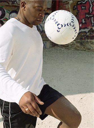 Man juggling soccer ball in front of graffitied wall Stock Photo - Premium Royalty-Free, Code: 695-05776773