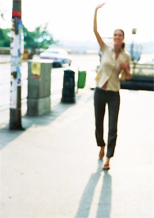 Woman on sidewalk, hand up, blurred Stock Photo - Premium Royalty-Free, Code: 695-05776942