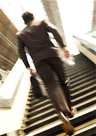 Businessman hurrying up stairs in train station, rear view, blurred motion Foto de stock - Sin royalties Premium, Código: 695-05777015