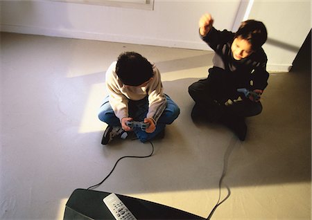 Young boys sitting on floor playing video game, high angle view Stock Photo - Premium Royalty-Free, Code: 695-05777059