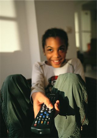 Young girl sitting, pointing remote control, smiling Foto de stock - Sin royalties Premium, Código: 695-05777073