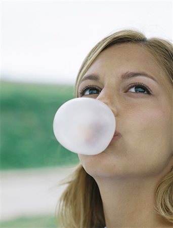 Young woman blowing bubble with chewing gum, looking up, close-up Stock Photo - Premium Royalty-Free, Code: 695-05777310