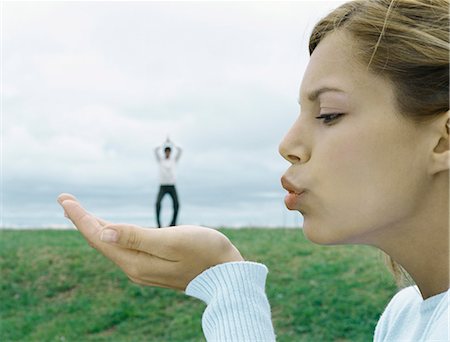 Woman blowing a kiss, man in distant background, optical illusion Stock Photo - Premium Royalty-Free, Code: 695-05777313