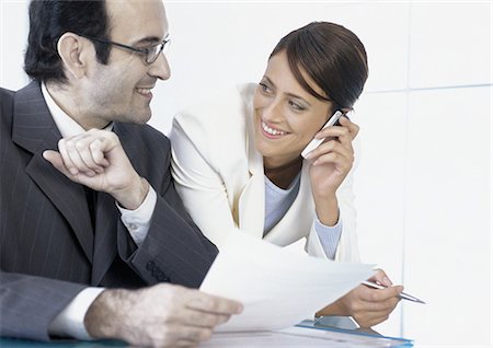 simsearch:859-06710917,k - Businesswoman talking on cell phone smiling at businessman next to her Stock Photo - Premium Royalty-Free, Code: 695-05777600