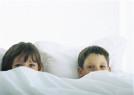 Boy and girl lying in bed, faces partially covered by duvet Stock Photo - Premium Royalty-Free, Code: 695-05777671