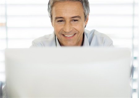 face to internet technology - Middle-aged man using laptop Stock Photo - Premium Royalty-Free, Code: 695-05778797
