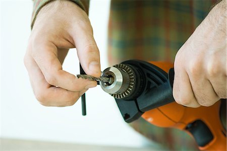 Man adjusting drill bit, cropped view of hands Stock Photo - Premium Royalty-Free, Code: 695-05779194