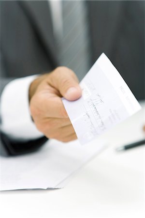 Businessman holding out check, cropped view of hand Stock Photo - Premium Royalty-Free, Code: 695-05779369
