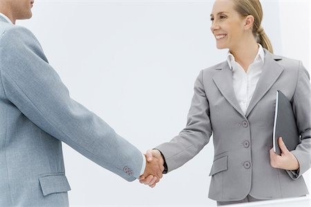 Businesswoman shaking hands with businessman, cropped side view Stock Photo - Premium Royalty-Free, Code: 695-05779473