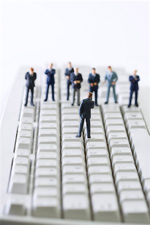 Miniature businessman addressing group of colleagues on computer keyboard Stock Photo - Premium Royalty-Free, Code: 695-05779549