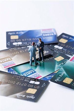 Miniature businessmen shaking hands on pile of credit cards Stock Photo - Premium Royalty-Free, Code: 695-05779552
