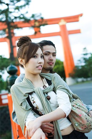 Young couple leaning against railing together, traditional Japanese Torii gate in background Stock Photo - Premium Royalty-Free, Code: 695-05779611