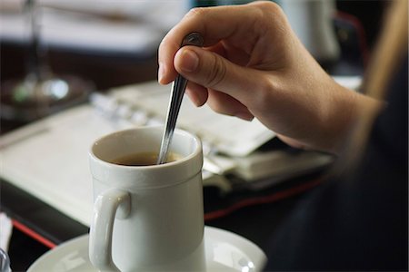 Hand stirring coffee, agenda on table in background, close-up Stock Photo - Premium Royalty-Free, Code: 695-05779671