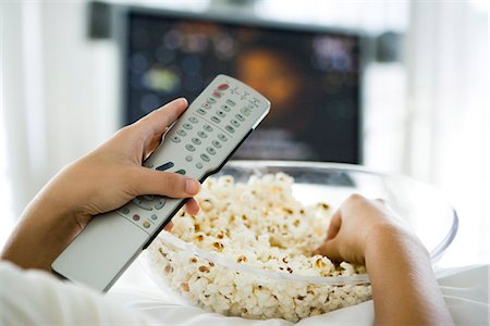personal perspective - Person watching television, holding remote control and bowl of popcorn, cropped view Stock Photo - Premium Royalty-Free, Code: 695-05779722
