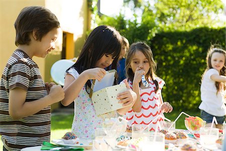 Girl opening gift at birthday party as friends watch Stock Photo - Premium Royalty-Free, Code: 695-05779971