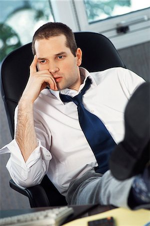 Man with feet up on office desk holding head looking away Stock Photo - Premium Royalty-Free, Code: 695-05770012