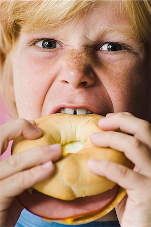 Boy biting into ham and cheese bagel sandwich, close-up Foto de stock - Sin royalties Premium, Código: 695-05770281