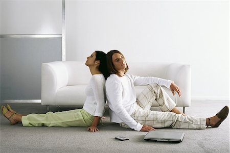 Couple sitting back to back on floor Stock Photo - Premium Royalty-Free, Code: 695-05770367