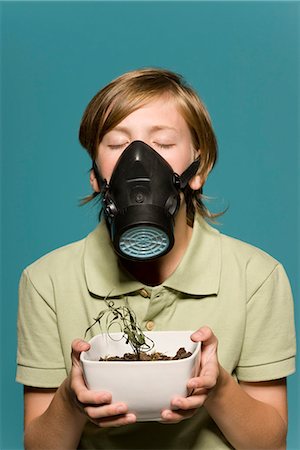 Boy wearing gas mask, holding wilted potted plant Foto de stock - Sin royalties Premium, Código: 695-05770684