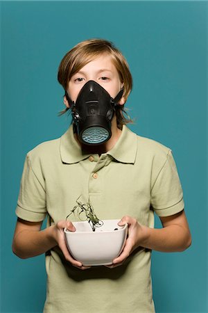 Boy wearing gas mask, holding wilted potted plant Foto de stock - Sin royalties Premium, Código: 695-05770685