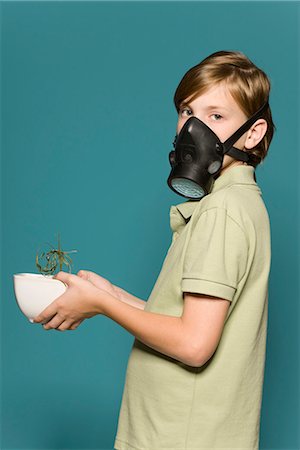 Boy wearing gas mask, holding wilted potted plant Stock Photo - Premium Royalty-Free, Code: 695-05770687