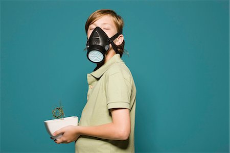 Boy wearing gas mask, holding wilted potted plant Foto de stock - Sin royalties Premium, Código: 695-05770688