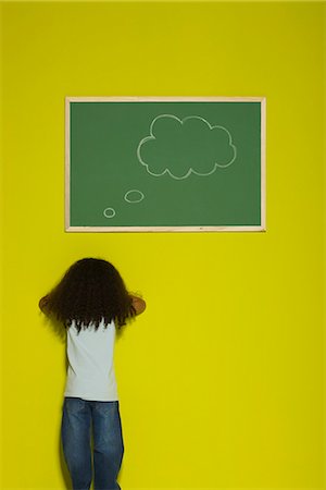 Little girl facing wall, thought bubble on chalkboard Stock Photo - Premium Royalty-Free, Code: 695-05770701