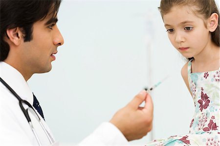 Pediatrician showing little girl syringe Stock Photo - Premium Royalty-Free, Code: 695-05770763