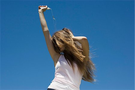 Young woman listening to MP3 player, dancing outdoors Foto de stock - Sin royalties Premium, Código: 695-05770848