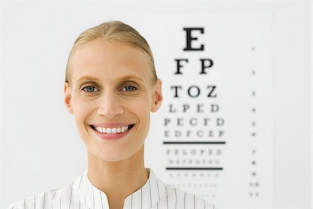 eye exam - Young woman, eye chart in background, portrait Stock Photo - Premium Royalty-Free, Code: 695-05771269