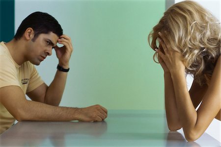 splitting - Upset couple sitting at table, both holding heads Stock Photo - Premium Royalty-Free, Code: 695-05771416