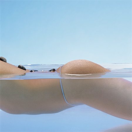 pot belly - Woman in water doing lastone therapy, close-up of mid-section, side view Foto de stock - Sin royalties Premium, Código: 695-05772715