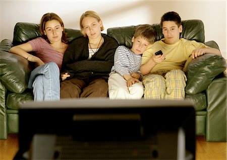 Focus on young adults and children sitting on couch in background, rear view of television in foreground, blurred. Foto de stock - Sin royalties Premium, Código: 695-05772868