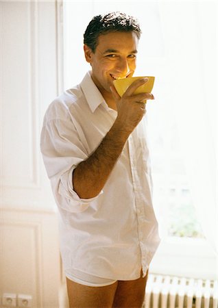 Man wearing buttondown shirt and underwear, holding bowl to mouth, smiling Stock Photo - Premium Royalty-Free, Code: 695-05773018