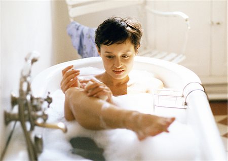 Woman taking bath, holding leg out of water Stock Photo - Premium Royalty-Free, Code: 695-05773047
