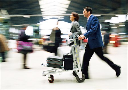 simsearch:695-05773315,k - Businessman and businesswoman walking together with luggage through station, blurred. Stock Photo - Premium Royalty-Free, Code: 695-05773287